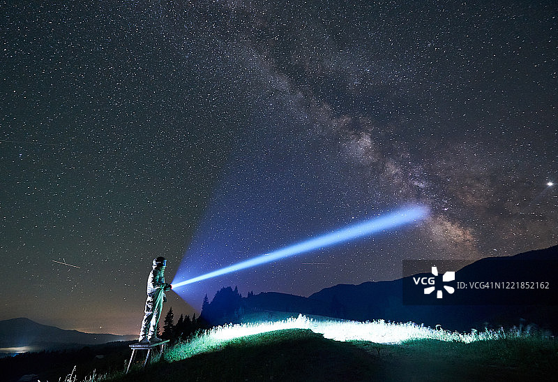 太空旅行者用手电筒照亮雄伟的夜空。图片素材