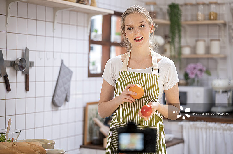 年轻的女性美食专家在网上做视频，用摄像机向网上的粉丝解释烹饪过程。分享和教学在线学习。图片素材
