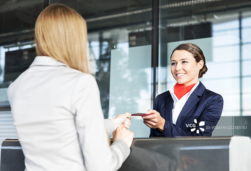 旅客服务代理人在机场的值机区出示女士的护照和登机牌图片素材