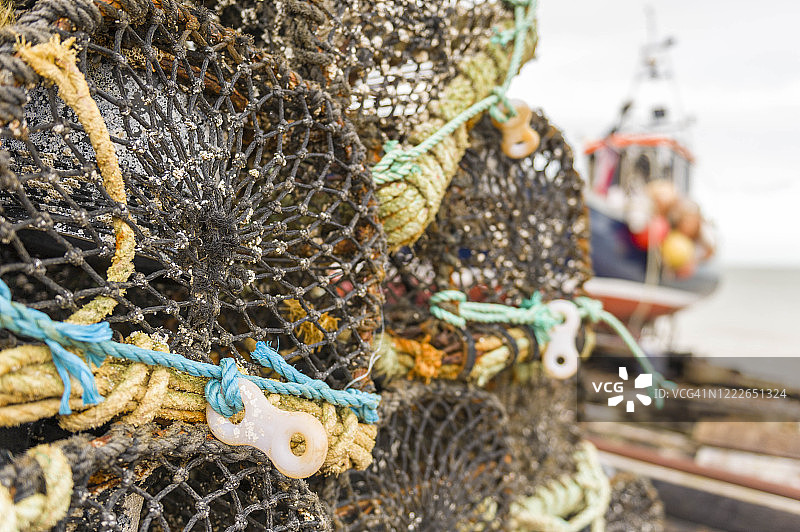 迪尔，英国肯特，2012年12月30日。龙虾锅，捕鱼设备和背景渔船在迪尔海滩。图片素材