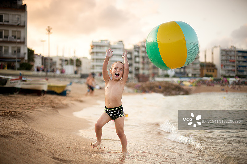 非常兴奋的男孩带着一个大球在海滩上图片素材