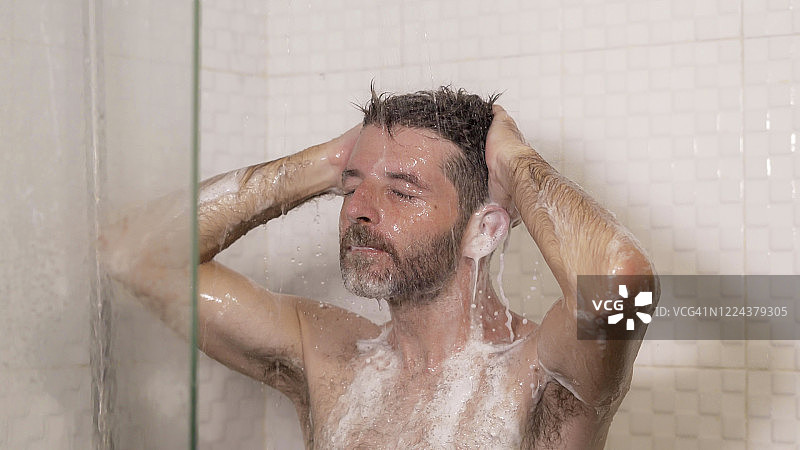 早上淋浴-生活方式肖像年轻有吸引力和快乐的男人胡子在家里洗澡，用洗发水洗他的头发享受快乐的健康和卫生概念图片素材