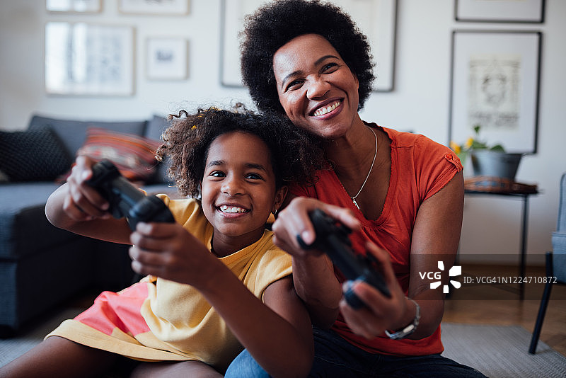 母亲和女儿一起玩电子游戏的正面画面图片素材