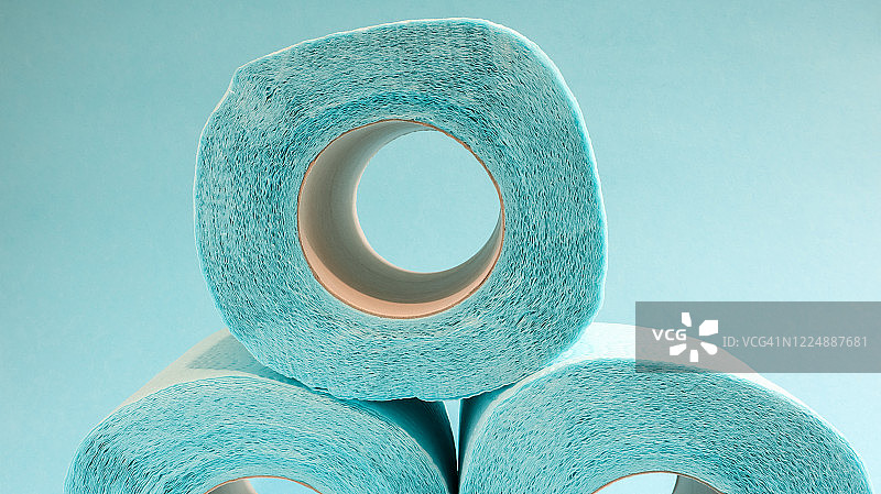蓝色背景上的蓝色现代卫生纸卷。一种贴在纸板套上的纸产品，用于卫生目的，由纤维素制成，带有易于撕裂的切口。压花画图片素材