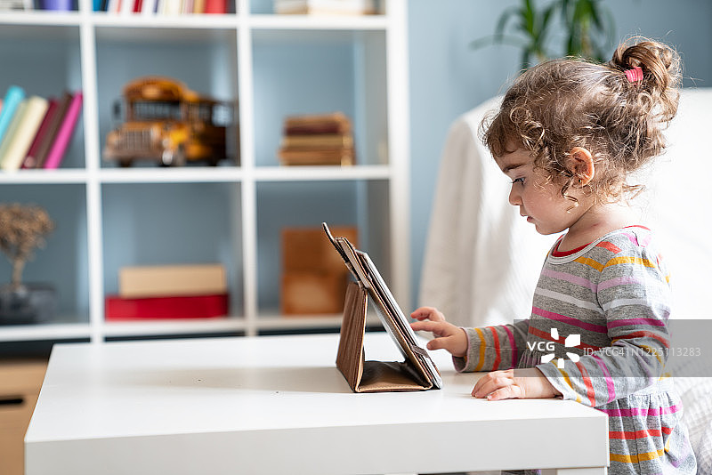 小女孩在客厅用平板电脑看教育视频图片素材