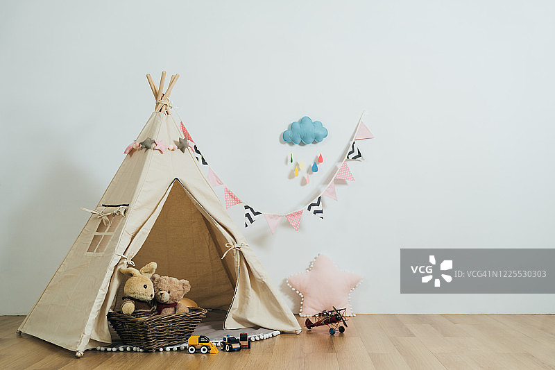 舒适气氛的儿童游戏室，游戏帐篷和填充玩具，白色的墙壁背景。空房间内部的孩子装饰可爱的配件。图片素材