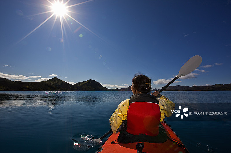 在冰岛中部寂静的湖面上划着海上皮艇的女子图片素材