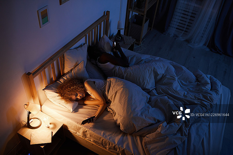 年轻夫妇晚上睡觉时用手机图片素材