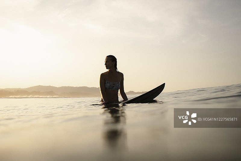 女冲浪者晚上坐在冲浪板上，哥斯达黎加图片素材
