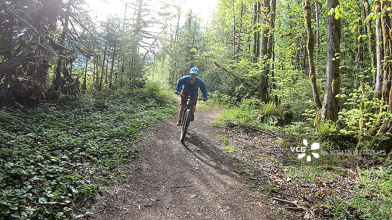 骑山地车的人骑着电动山地车沿着森林小径骑行图片素材