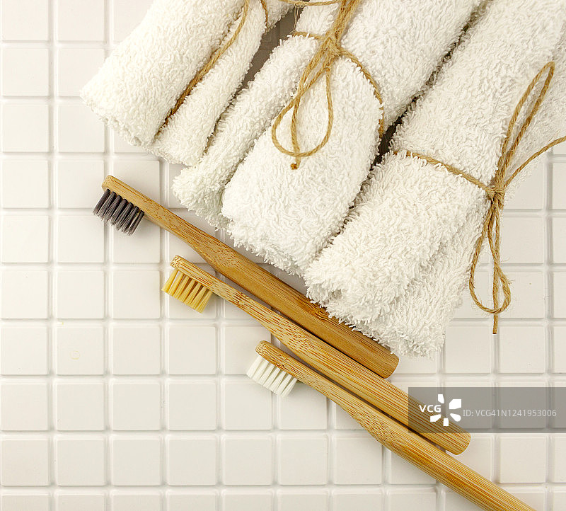 家庭设置竹牙刷，白毛巾瓷砖背景。生态友好概念平铺图片素材