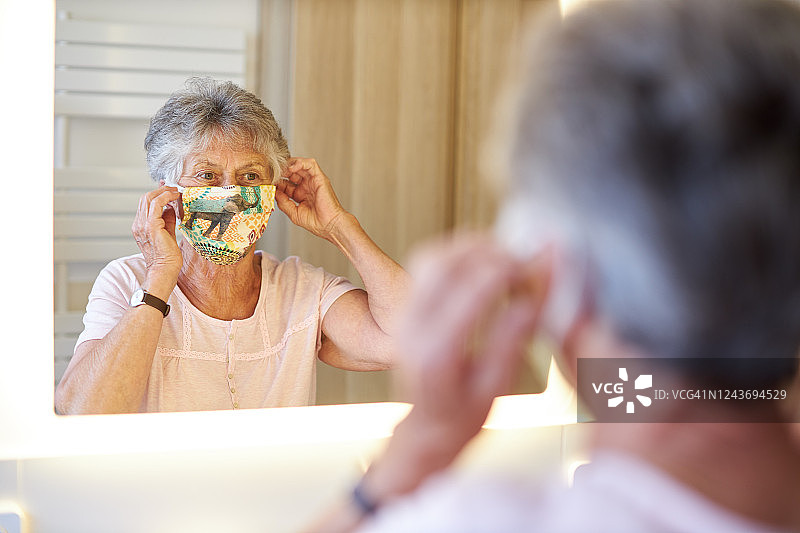 不同的照片，一个中年男人，一个中年女人和一个祖母，他们戴着不同的防护面具或面罩在镜子前图片素材