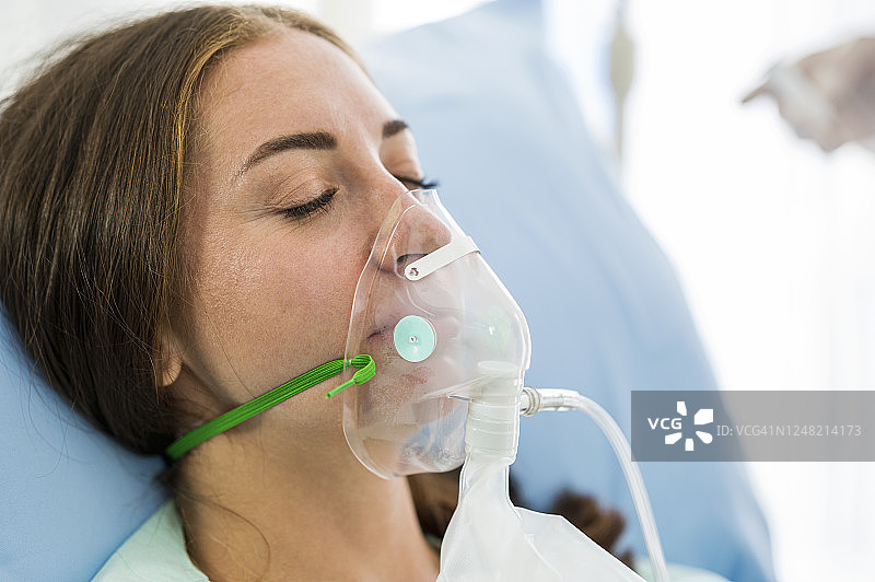 昏迷的女病人戴着氧气面罩躺在医院的病床上图片素材