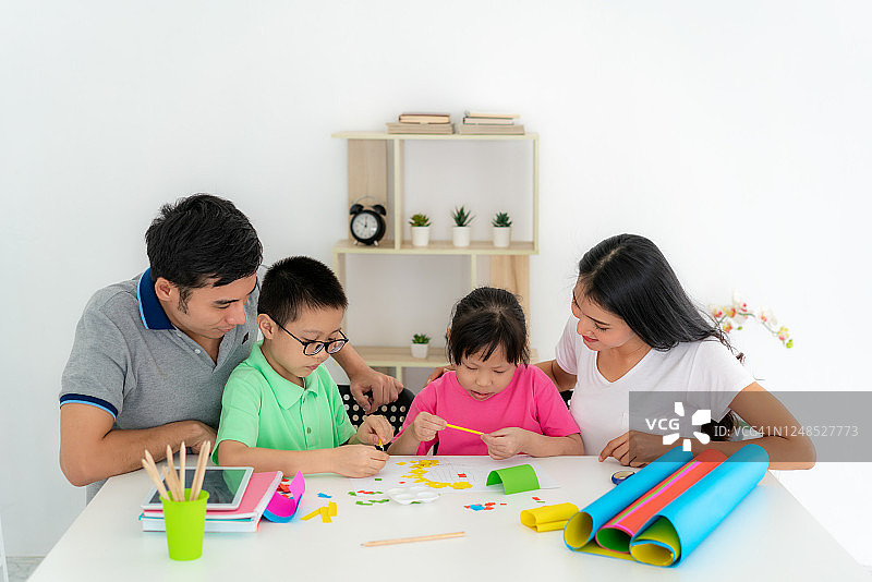 亚洲家庭与父亲，母亲，女儿和儿子编辑彩色纸制作艺术品，并参与手工艺项目和奖励活动在家自学。图片素材