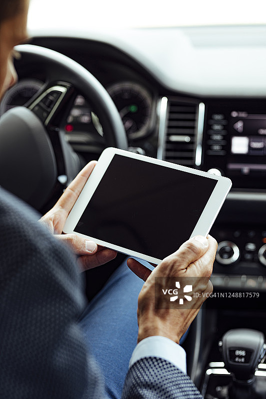 汽车中的技术:一个匿名商人坐在驾驶座上使用数字平板电脑图片素材