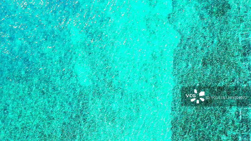 美丽的海洋纹理充满活力的水在绿松石礁湖表面与珊瑚礁图案水下反射阳光，复制空间图片素材