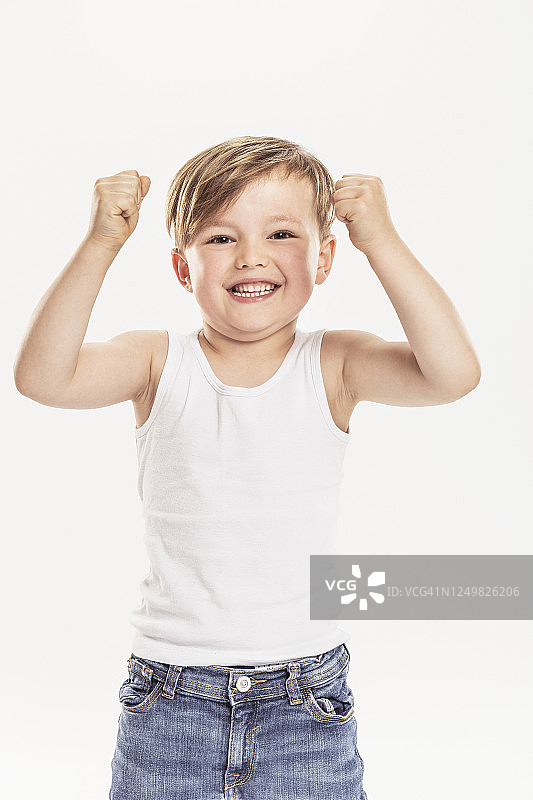小男孩紧握拳头站在白色背景前的肖像图片素材