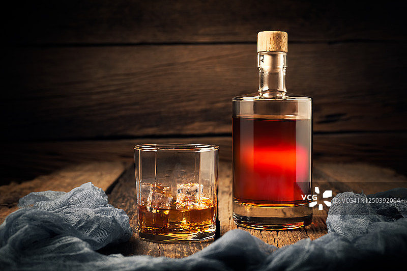 靠近木墙的木桌上放着威士忌酒杯和威士忌酒瓶。图片素材