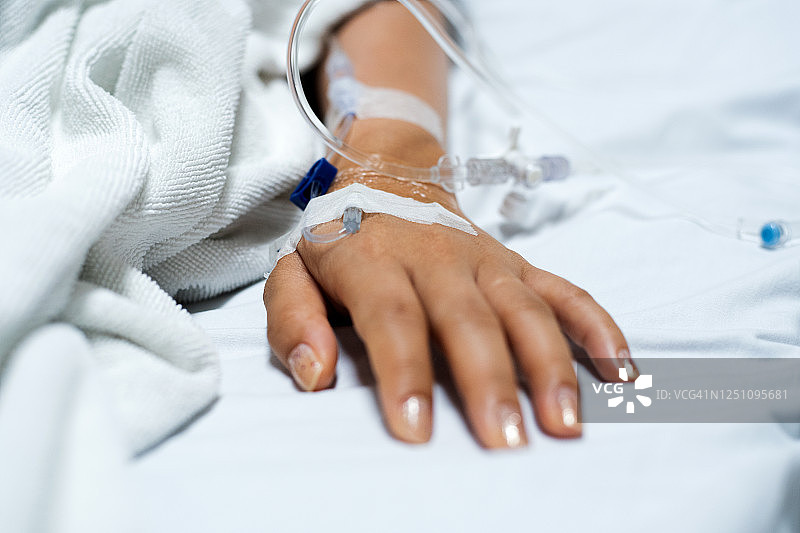 在医院接受静脉滴注药物的病人的手的特写图片素材