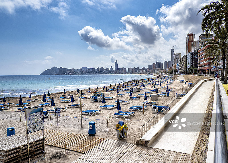 西班牙贝尼多姆波尼恩特海滩上的海滨长廊和海滩，映衬着蓝天。图片素材