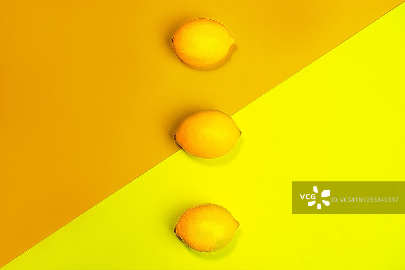 明亮的黄色背景上柠檬的创意图案。图片素材