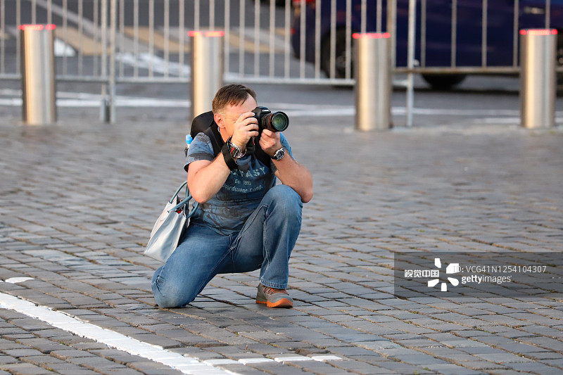 夏日的街道上，男摄影师正看着镜头。图片素材