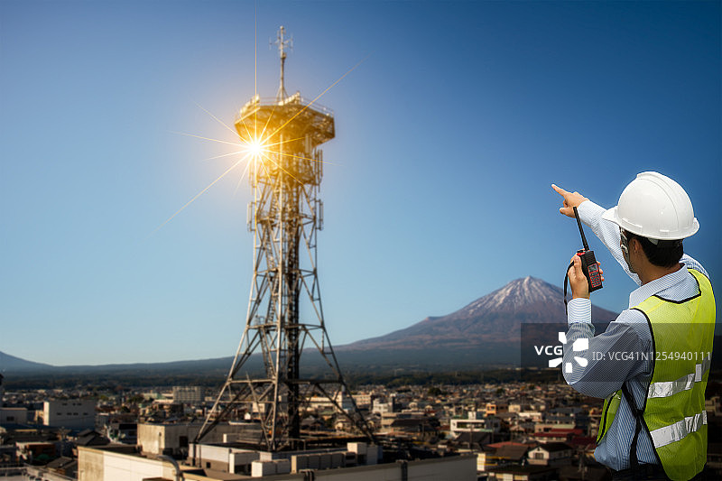 工程师通信检查天线是否有富士山背景。图片素材