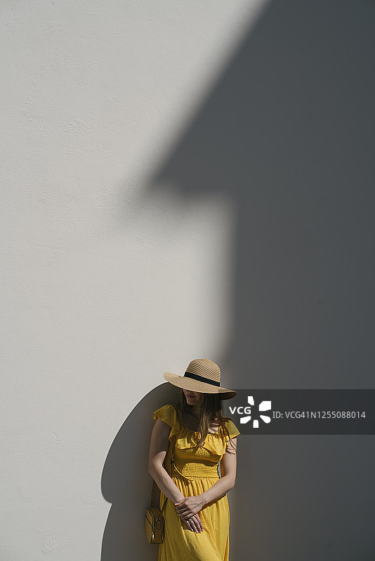女游客戴着帽子靠墙站在城市里图片素材