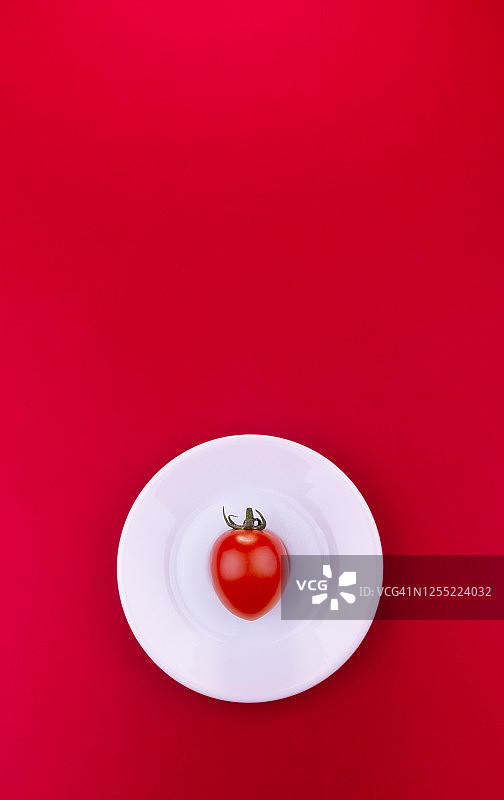 白色盘子上的樱桃番茄，红色背景图片素材