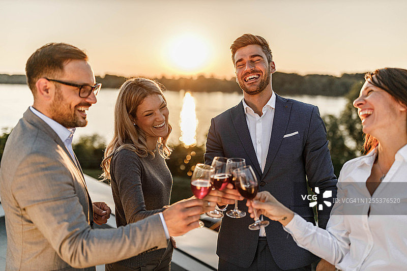 快乐的企业家们在阳台上用红酒敬酒。图片素材