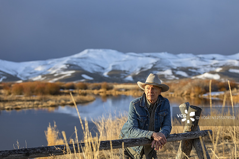 美国，爱达荷州，太阳谷，戴牛仔帽的老人靠在篱笆上图片素材