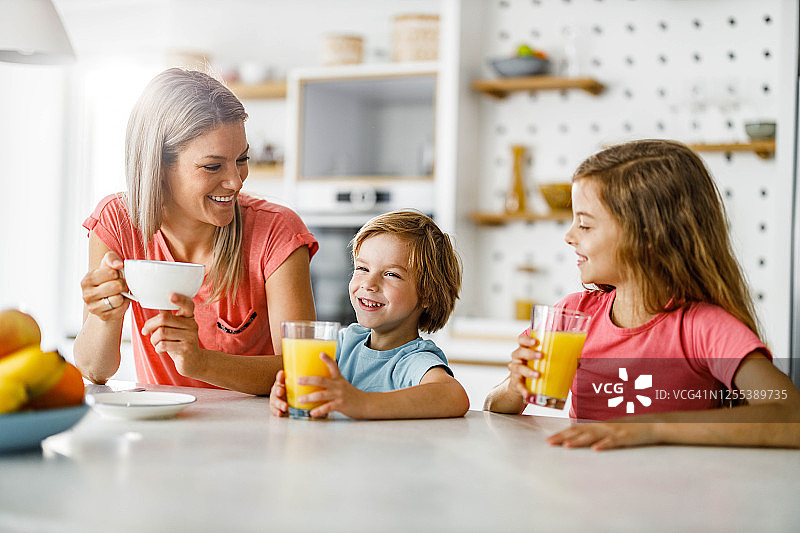 快乐的单身母亲在早上和她的孩子在厨房享受。图片素材