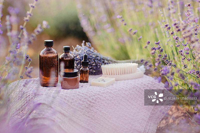 有机化妆品瓶，精油和肥皂在薰衣草田在夏天。芳香疗法。护肤概念。图片素材