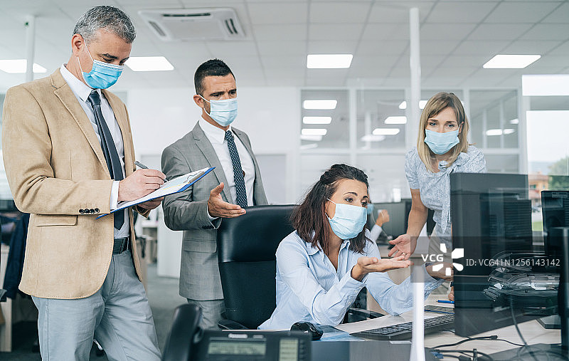 办公室里戴医用口罩的同事，新冠肺炎期间的新工作规则图片素材