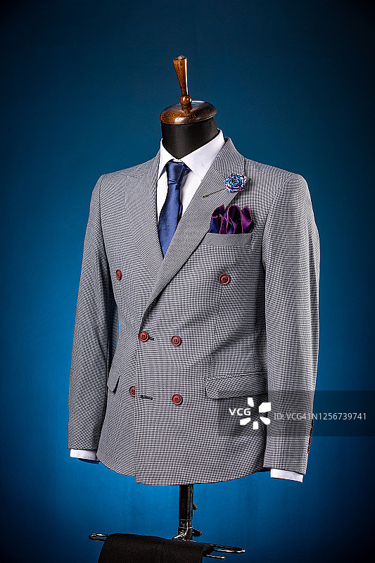 漂亮的男士灰色夹克西装，衬衫和领带上的假人或模特在蓝色背景图片素材