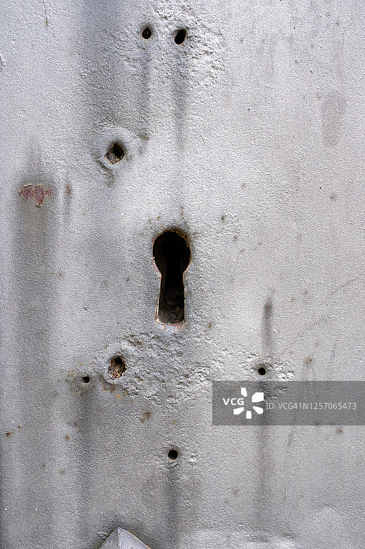 一个生锈的金属门锁的垂直图片，侧面有一些洞图片素材