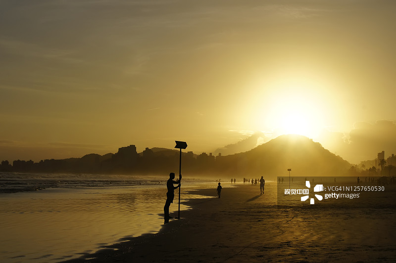 游客有乐趣的阿斯图里亚斯海滩Guarujá在日落。图片素材