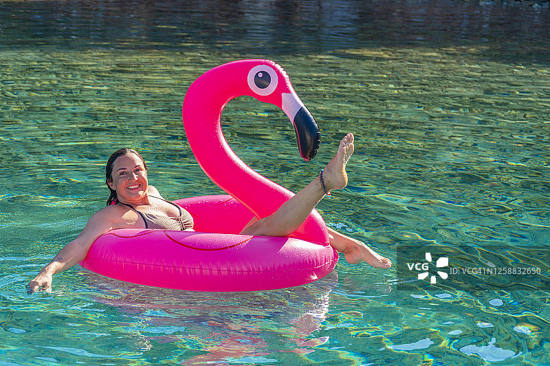 膨胀的粉红色火烈鸟和海里的可爱女人。图片素材