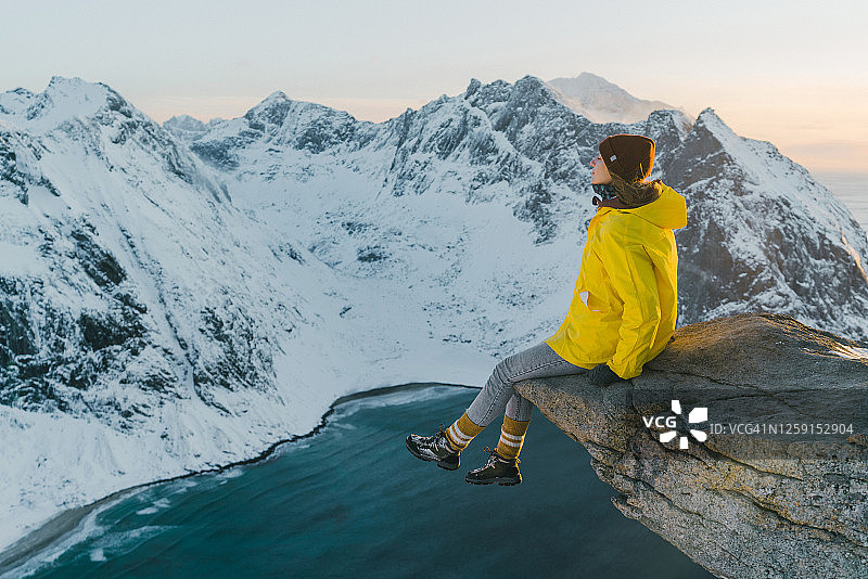 女人坐在悬崖上，看着罗弗敦岛的海边在雪图片素材
