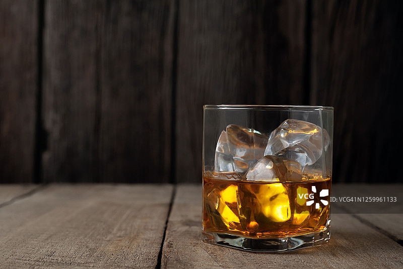 一个威士忌酒瓶靠在木桌上的特写。图片素材
