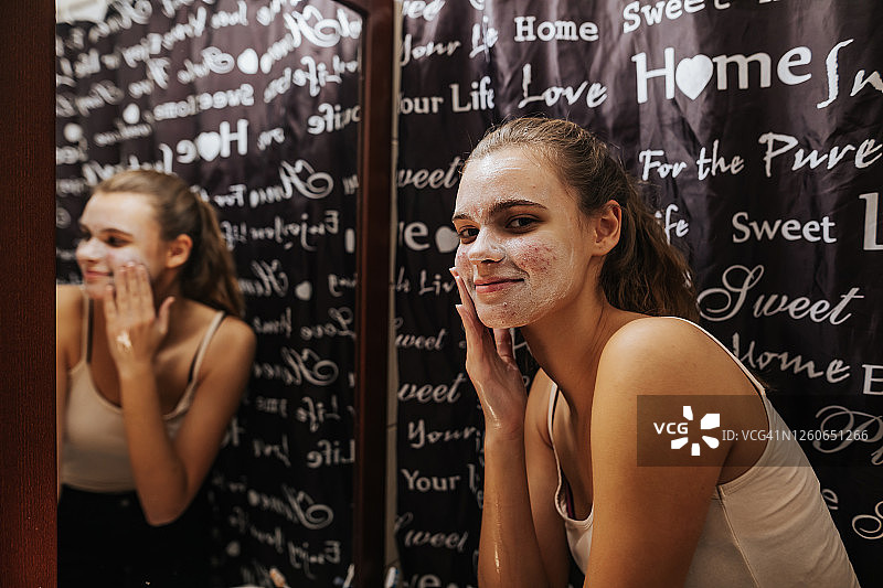 微笑的少女在浴室里用肥皂洗脸图片素材