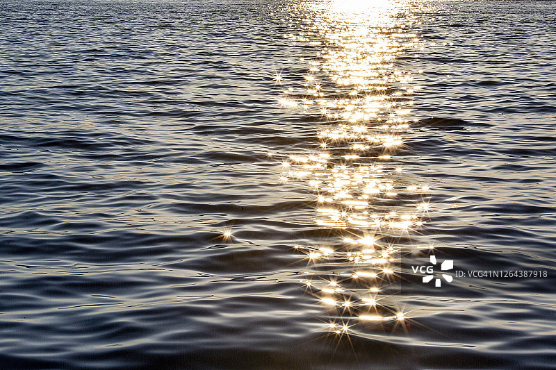海洋在闪烁，阳光反射出清澈的蓝色的水图片素材