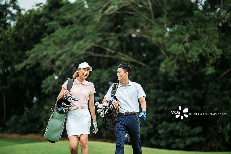 亚洲华人微笑年轻夫妇高尔夫球愉快地走在一起在高尔夫球场图片素材