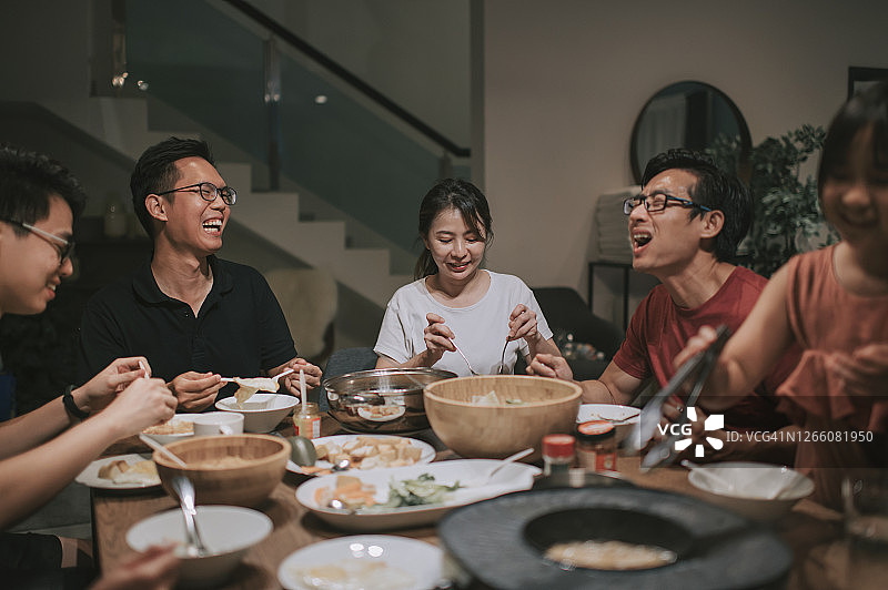 一个亚洲华人家庭和朋友在家里吃着传统的中国汽船菜共进晚餐图片素材