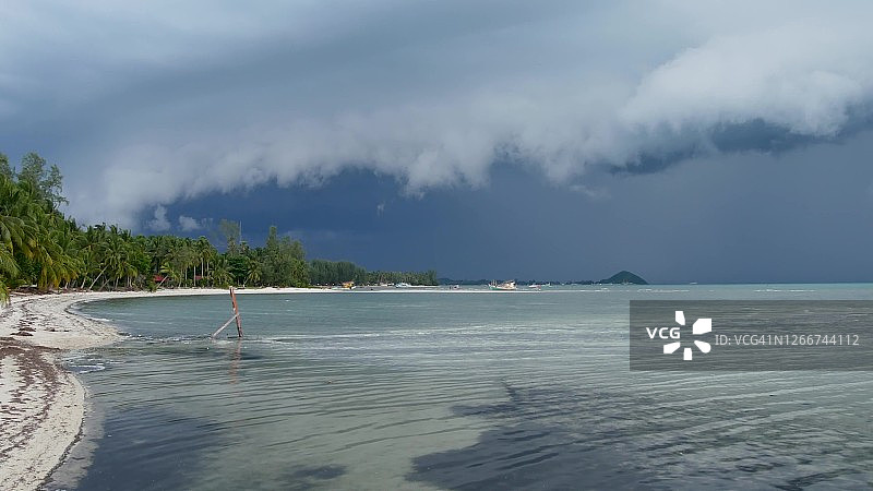 在泰国雨季，苏梅岛的沙滩上，波浪起伏的蓝色大海。热带海岸发出飓风及风暴警告。疾风和不祥的云。台风危险雷雨图片素材
