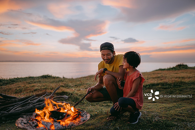 日落时分，父亲和女儿在海边露营地享受篝火图片素材