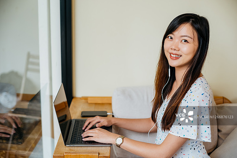 年轻的亚洲女人在咖啡馆使用笔记本电脑图片素材