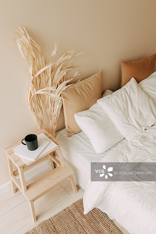 明亮的卧室室内，植物装饰，米色的织物，枕头，毯子，舒适舒适图片素材