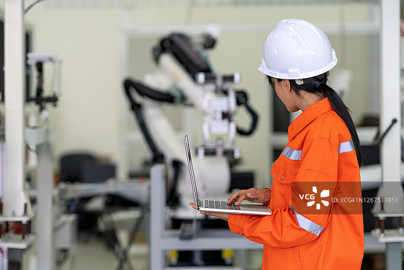 专业人员检查机器人在制造工厂的夹具基地上移动。这篇文章是为编程和检查质量的正确位置。图片素材