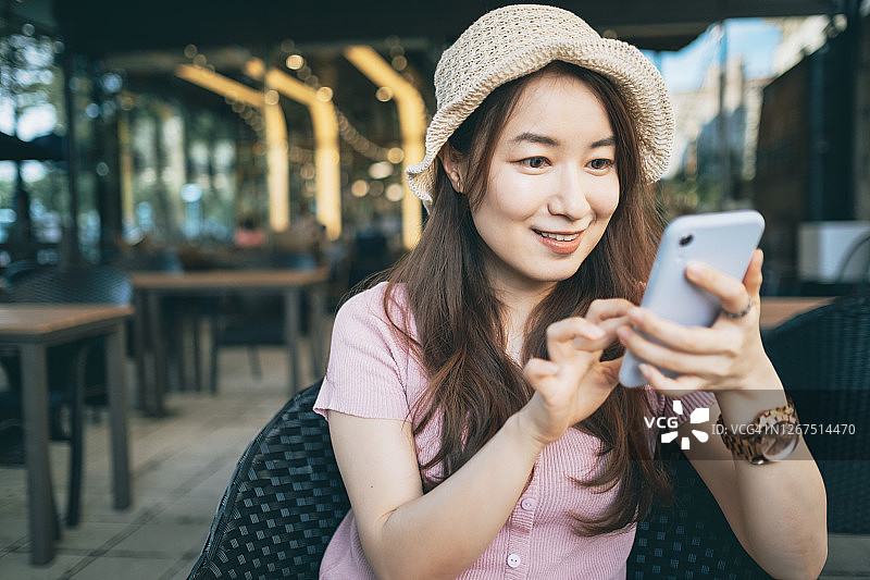 年轻女子坐在咖啡馆里使用智能手机图片素材